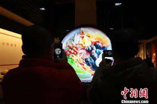 资料图：民众用手机拍摄螺蛳粉展示图。　朱柳融 摄